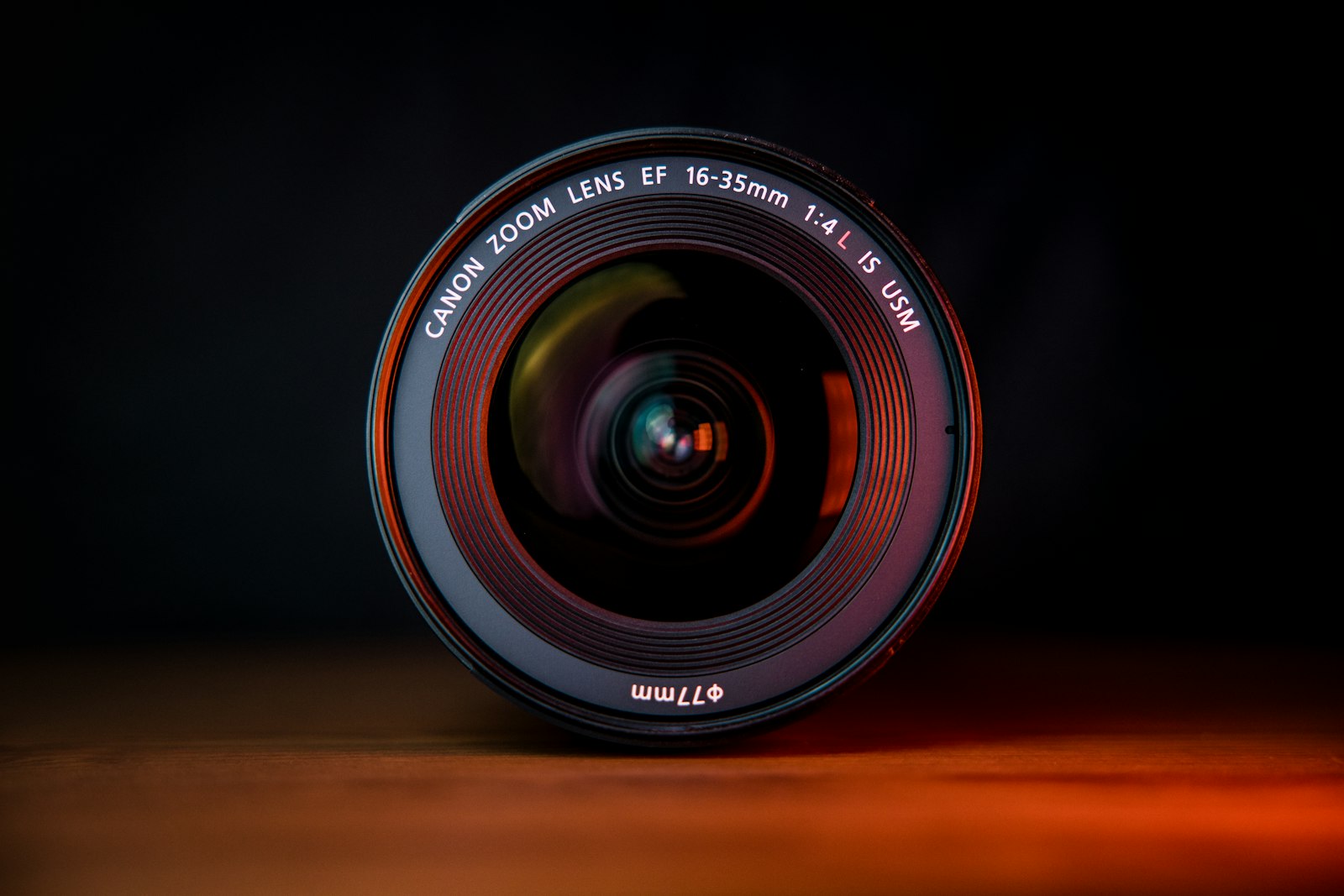 Black camera lens resting on a wooden table